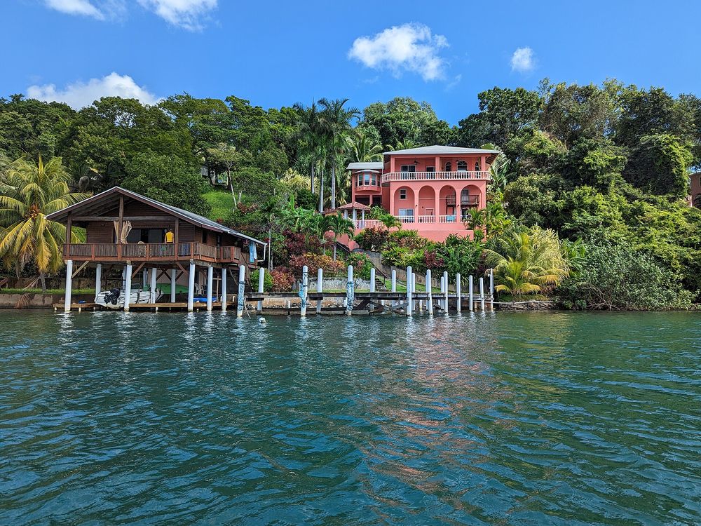 Pink two-story house above a wooden dock and stilt house in Oak Ridge, Roatán